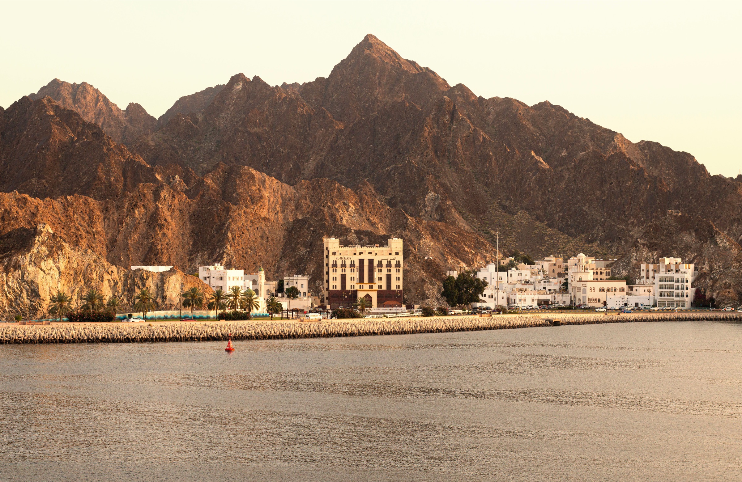 Muscat’s waterfront and mountains in warm evening light